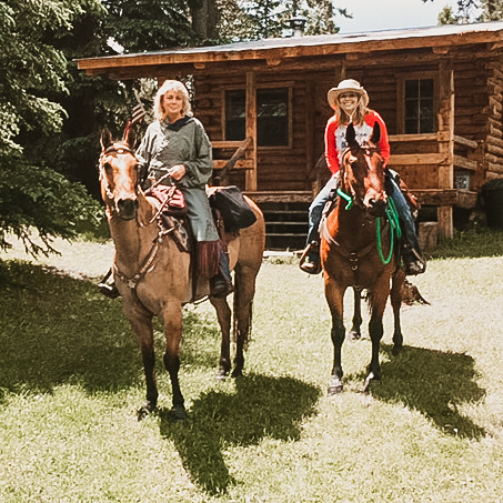 Manager Ami and owner Cindy pose with their horses in front of the Line Shack cabin at Hay Creek Ranch.