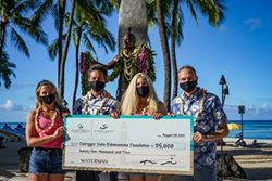 Two women and two men wearing face masks are holding a giant check noting the donation from the GSD.
