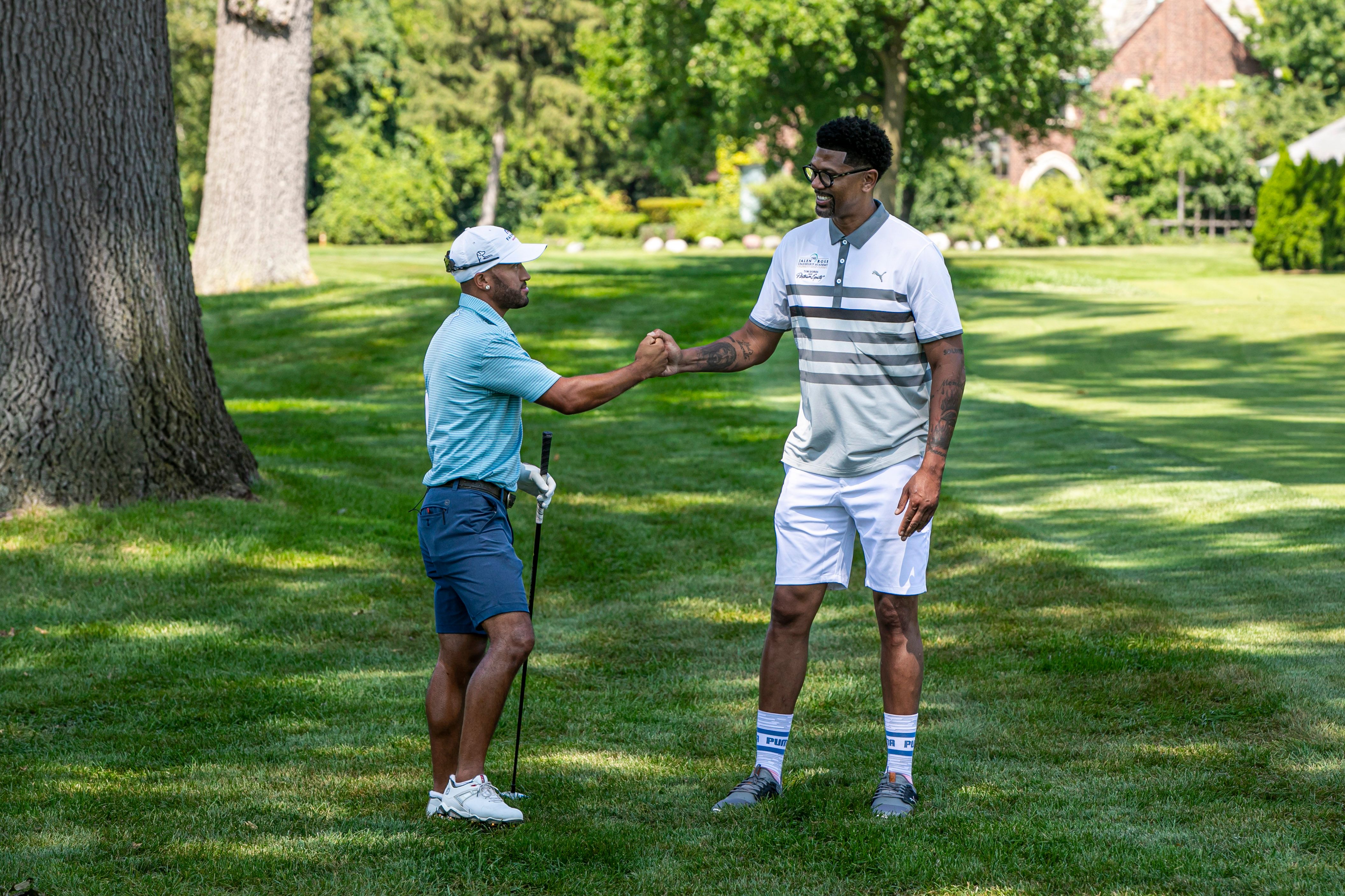 Jalen Rose (L) and Willie Mack 3 (R) fist-bump in the fairway at Detroit Golf Club at the Jalen Rose Golf Classic, A PGD Global Production on August 23, 2021.