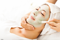 Woman lying back with eyes closed while getting a facial.