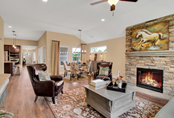 Stone fireplace and natural light warm an open plan living room / dining room of a 55+ model home.