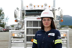 Crowley female employee with hard hat standing in front of the cab of her truck.