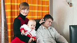 man working on a computer while a woman with a baby interrupts him