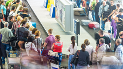 Travelers crowding baggage claim at airport.