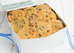 A white delivery box sits open with layers of Tiff's Treats cookies stacked inside.