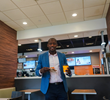 Pod Digital Media CEO Gary Coichy smiles with a coffee and food item while standing inside his first job, a McDonald's in Nyak, N.Y., where he worked as a drive-thru cashier.