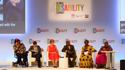 Six speakers at the Global Disability Summit (GDS) 2018 on a stage with the GDS logo behind them