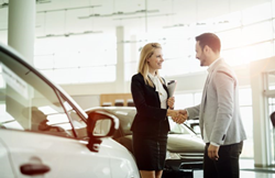 View of a representative and a customer shaking hands near a car.