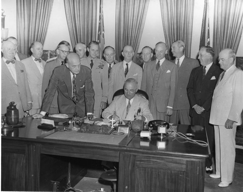 President Truman at his desk in the Oval Office signing National Security Act of 1949