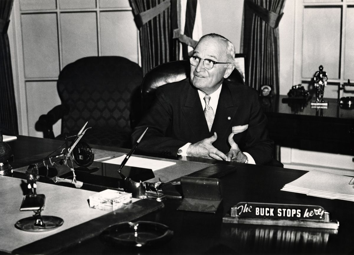 President Truman sitting in the reproduction of his office with "The Buck Stops Here" in the Harry S. Truman Presidential Library & Museum
