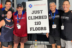 Group of people standing next to a sign that says, "Just Climbed 110 Floors"