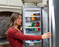 Woman looking into freezer.