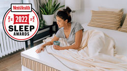 Woman lounging on an Essentia Organic Mattress with the Men's Health Sleep Award Logo in the top left corner of the image