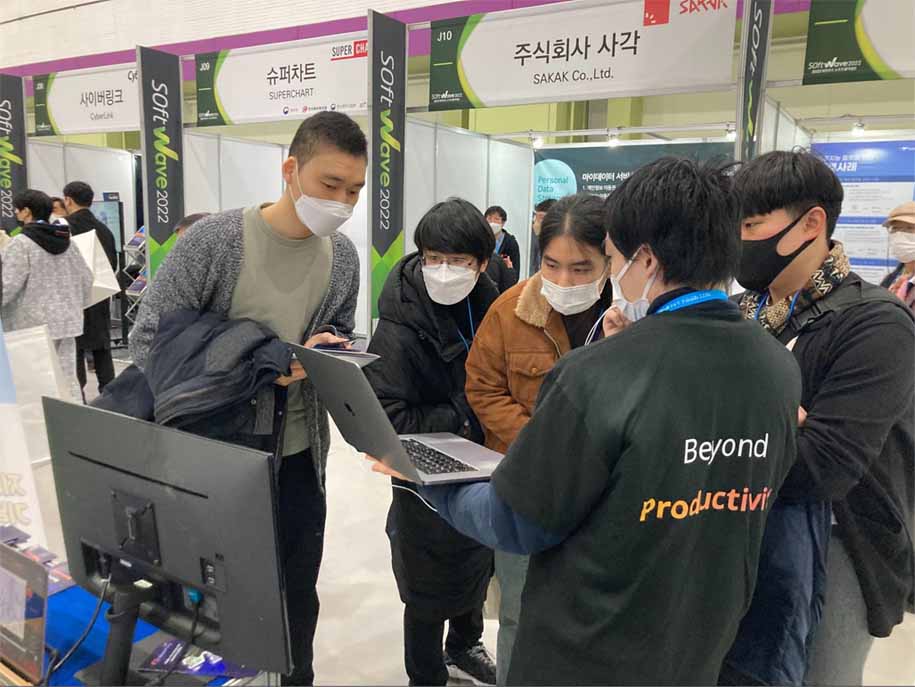 Japanese staff explaining VoicePing to a Korean visitor using the voice translation function