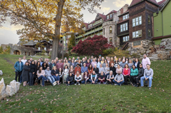 A group photo of Lantana Consulting Group employees standing on green grass in front of an old hotel