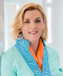 Professional head shot of woman in blue and orange blouse.