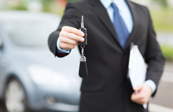 A man holding car keys in one hand and documents in the other.