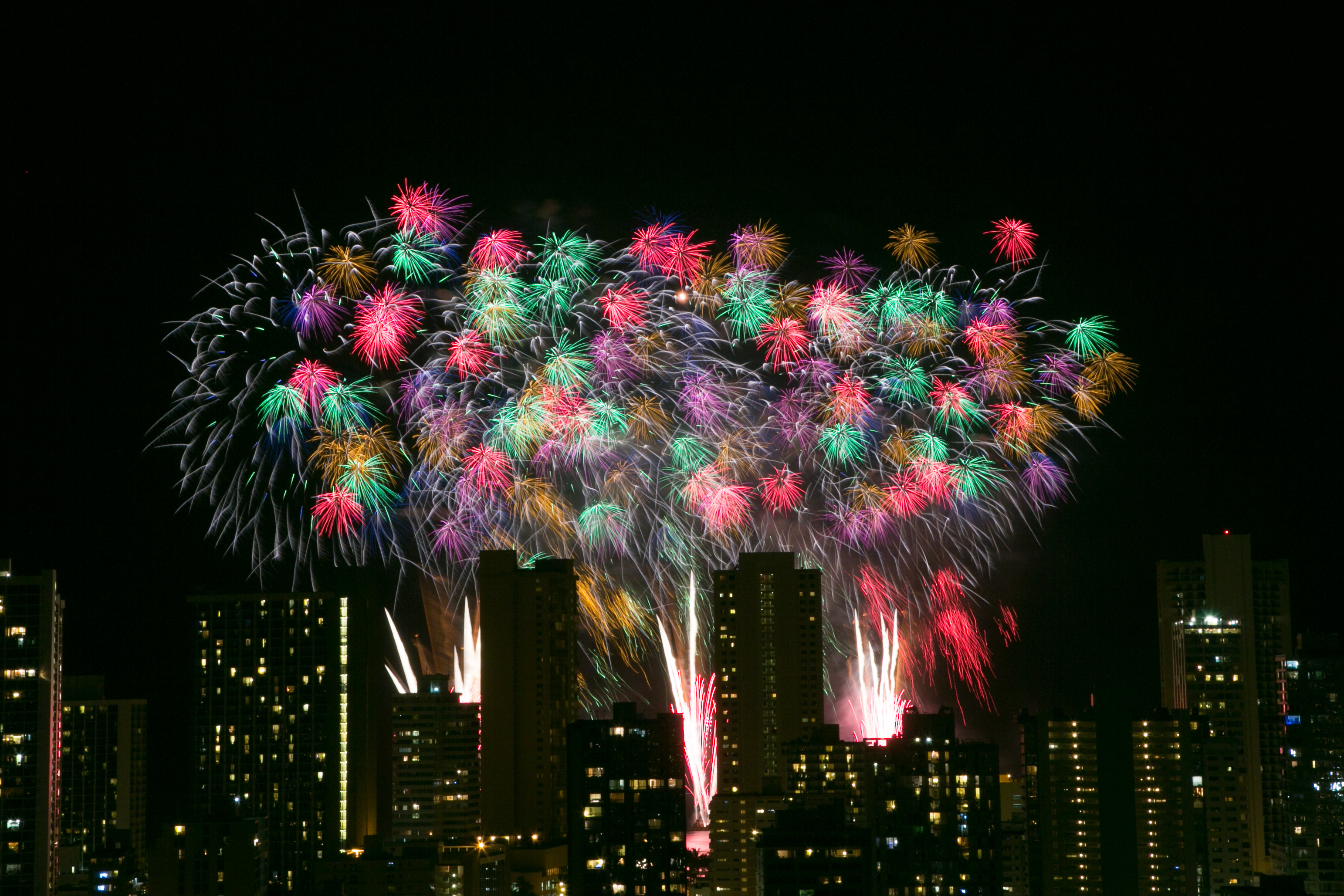 Pyrotechnic blooms light up the Honolulu skyline from the Nagaoka Fireworks Show.