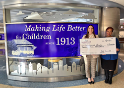 two women standing in front of a backlight sign that say's Making Life Better for Children since 1913.