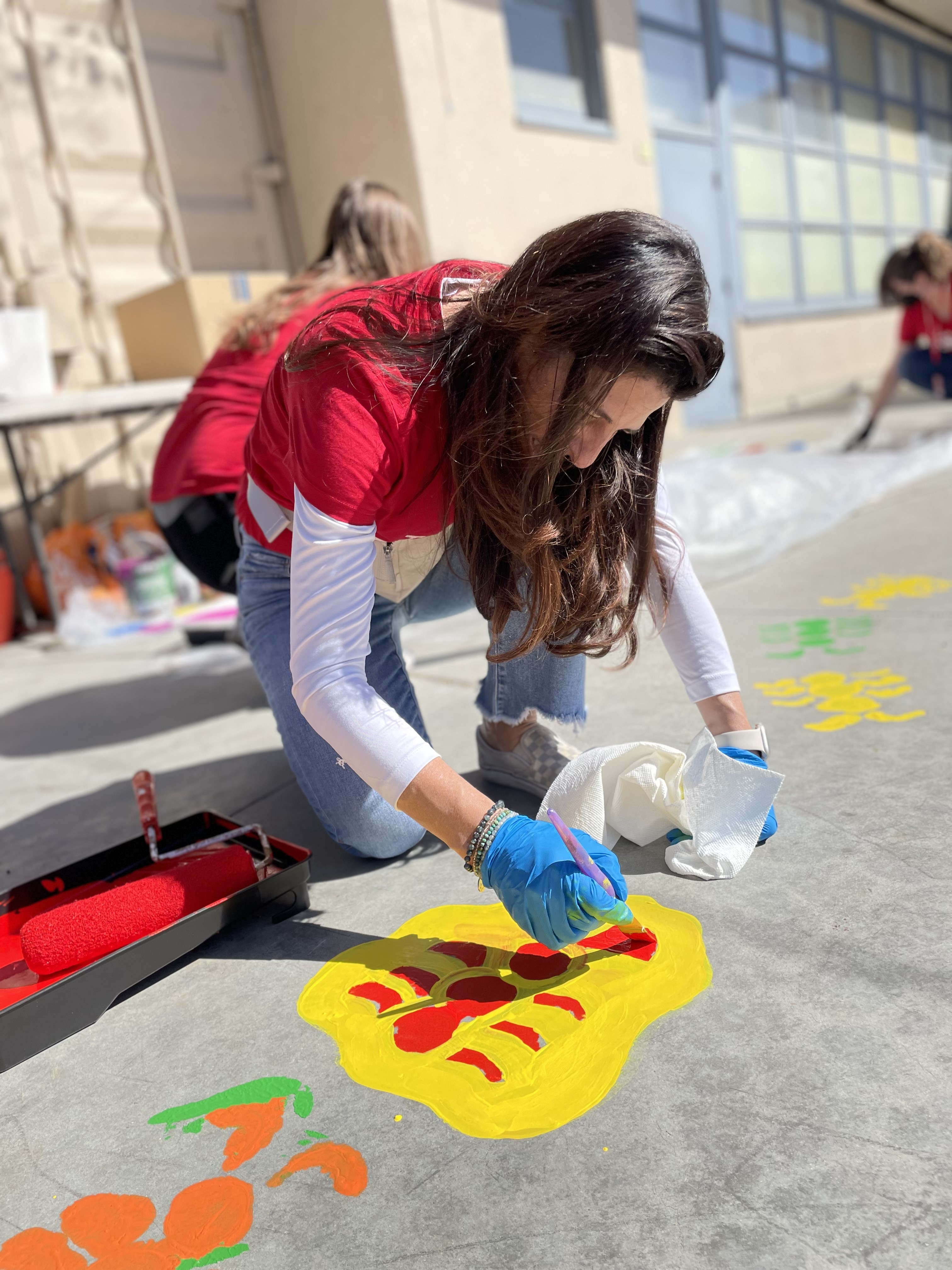 Volunteers paint a colorful agility course on the kinder playground.