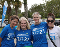 Four smiling women with matching tshirts pose for a photo at a previous APDA Optimism Walk.