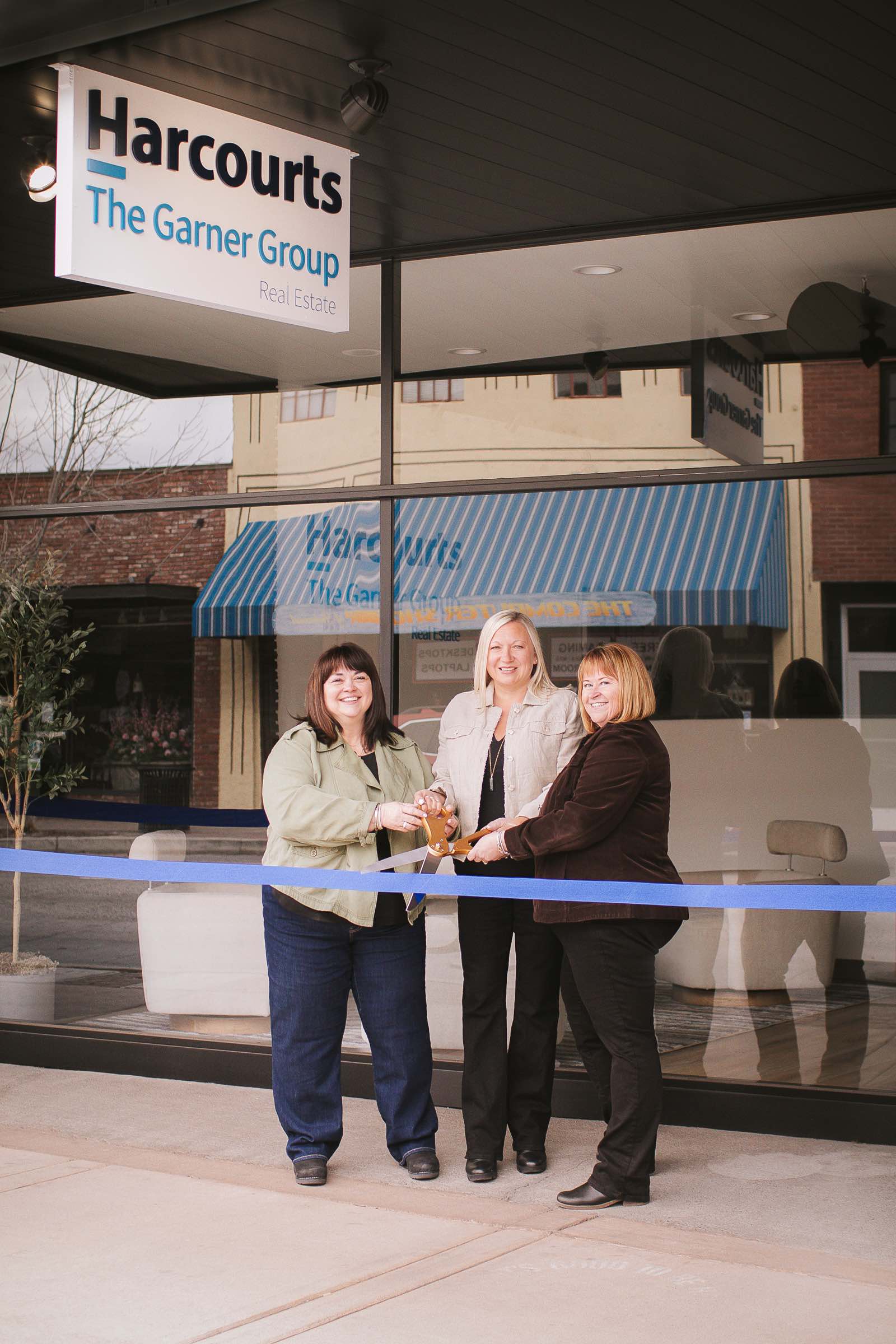 Co-owners from left to right, Shelley Griffin, Sara La Faver and Erica Davis cut the ribbon of the new Harcourt The Garner Group office in Redmond, Oregon; Photo credit: Emily Alper