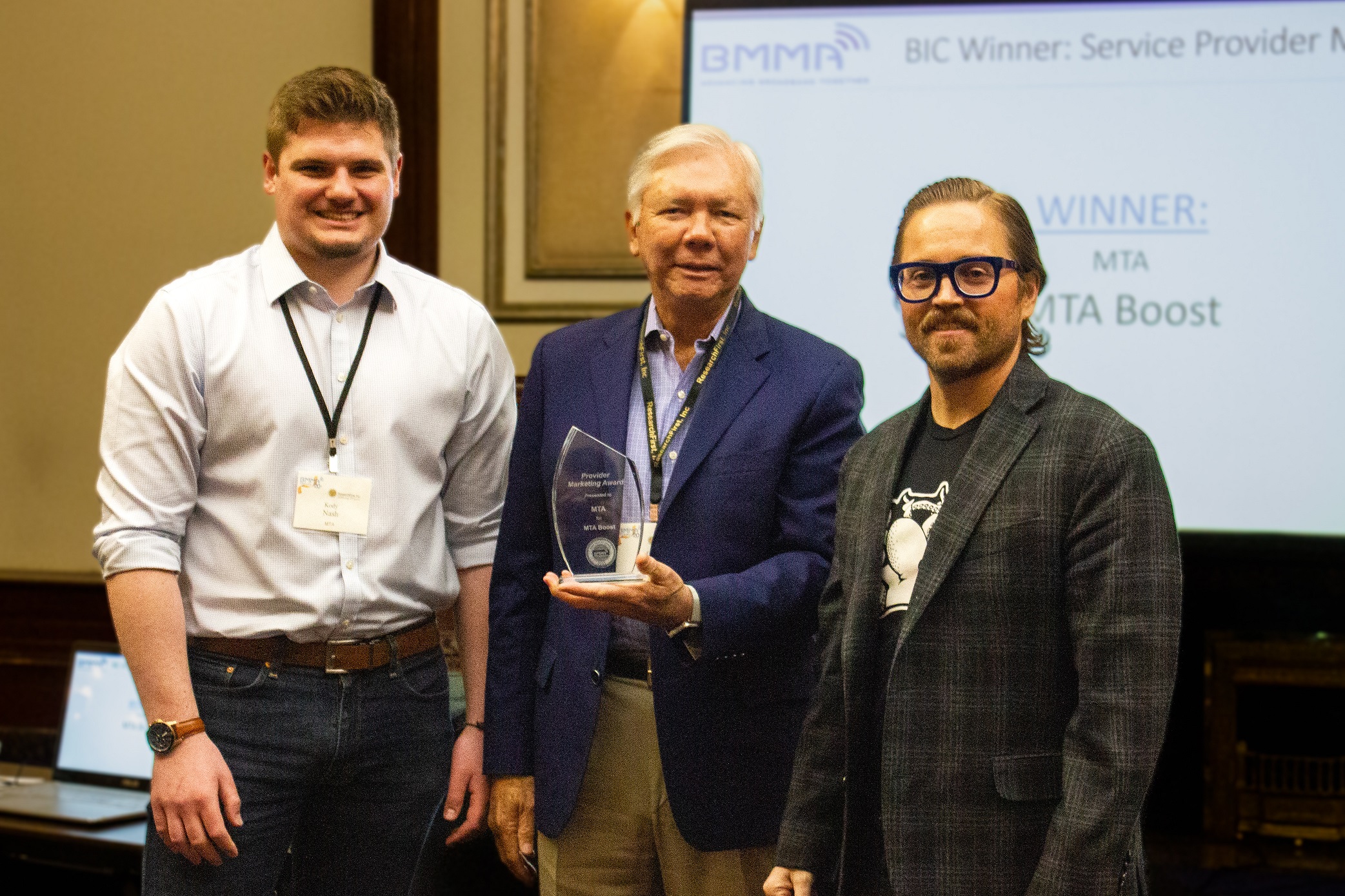 Kody Nash, Product Specialist (left) & Jonathan Babbitt, Vice President of Product Strategy & Communications of MTA (right) accept the Service Provider Award from Ellis Hill, President of RFI (center)