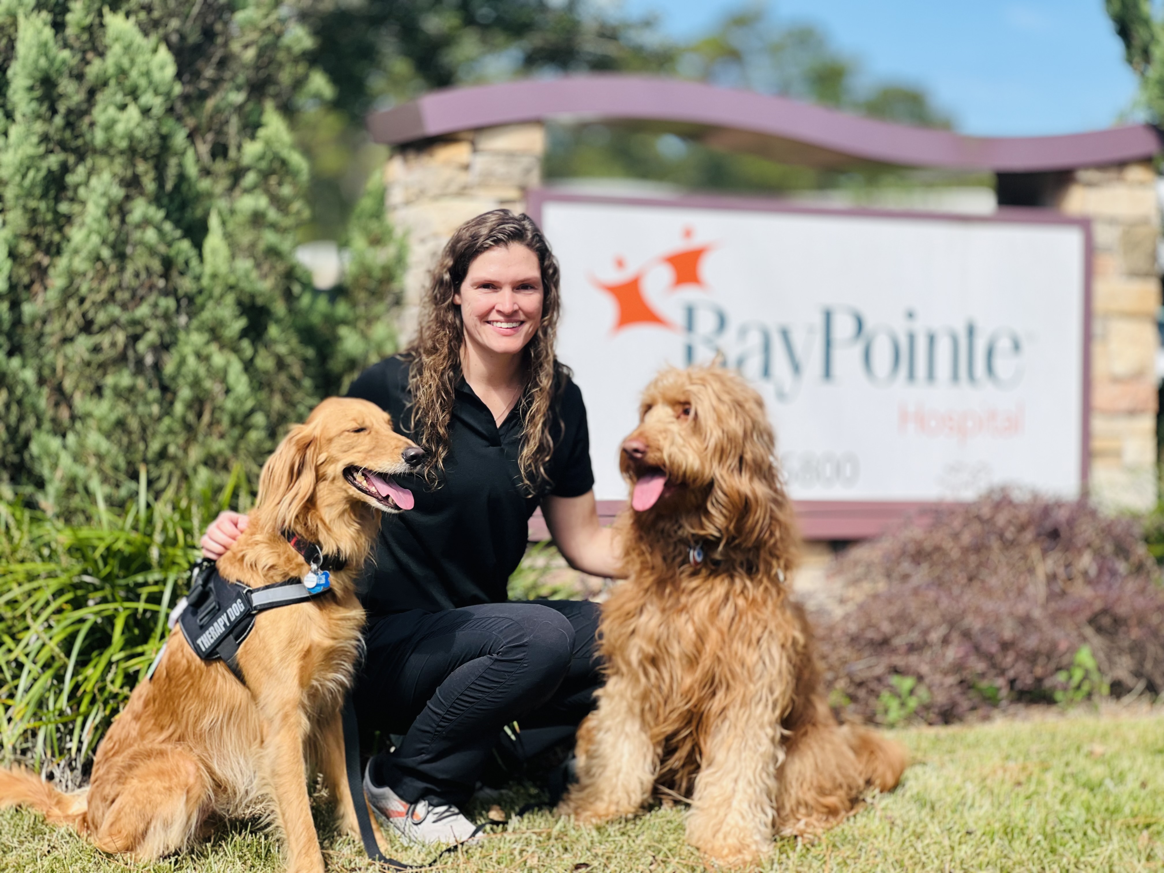 Megan James is pictured with her two Certified Pet Therapy goldendoodles, Zeke (left) and Ollie (right), that she trained to provide emotional support for both patients and fellow staff members.